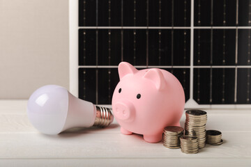 Solar panel on the background of a piggy bank, LED lamp and coins. Concept of saving money and...
