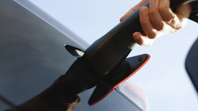 Close up of charging cable connecting to the electric vehicle for charging a battery. Type 2 plug port on electric vehicle. Fast charging socket type 2 electric car. Eco friendly alternative energy.
