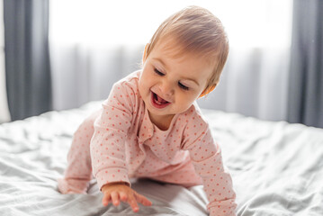 Fototapeta premium Portrait of a crawling baby on a bed in her room