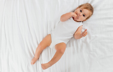 smiling newborn baby on a white bed at home, the concept of a happy, healthy baby, a place for text