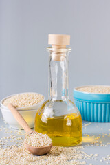 Sesame oil in a bottle and sesame seeds in a bowl on the table. Organic Alternative. Vertical view