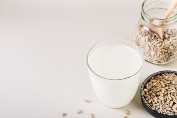 Dairy-free sunflower milk in a glass and seeds in a bowl on the table. Healthy food.