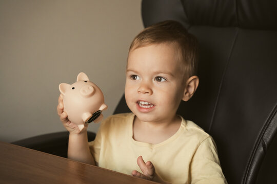 Child shakes piggy bank. Smart happy boy saving money in a piggy bank, learning about saving. Money, finances, insurance, and people concept