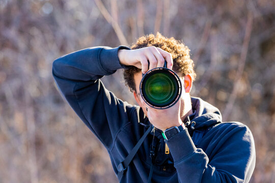 Young African American Photographer taking a photo outdoors pointed at the camera