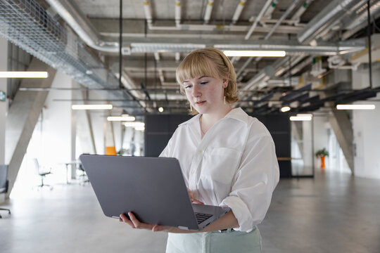 Young Nonbinary Businessperson Using Laptop In Modern Office