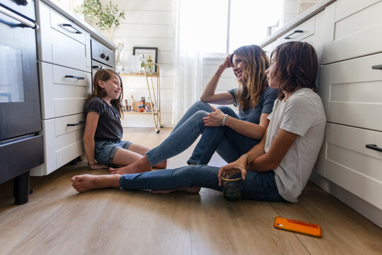 Mother, daughter and son bonding, talking on kitchen floor