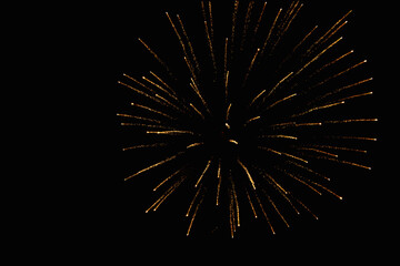 Firework at its maximum expansion of luminous yellow and red sparks on the night sky