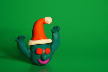 A toy virus in a Santa Claus hat is trying to scare. New Year decorations. Green background.