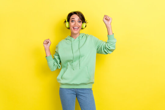 Photo of impressed overjoyed optimistic girl bob hairstyle wear green hoodie raise fists up yeah yell isolated on yellow color background