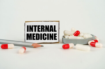 On a white background, medical capsules, a pencil and a cardboard plate with the inscription -...