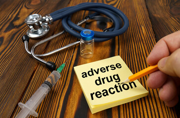 On the table is a stethoscope, a syringe and a sticker with the text - adverse drug reaction