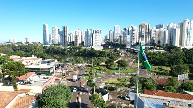 Bandeira do Brasil hasteada com vista para rotatoria da avenida Maringa em Londrina no Paraná sul do Brasil mostrando predios carros e ao fundo o lago igapó e céu azul