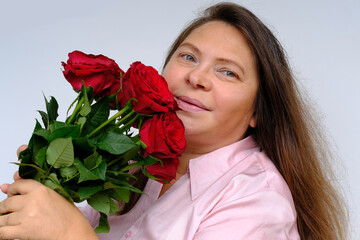 Fototapeta na wymiar bouquet of flowers, red roses in hands of happy funky mature woman 50 years old, having fun, festive mood with red roses, congratulations, mother's, Valentine's day, birthday, selective focus