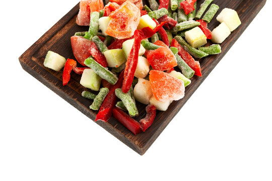 Different Frozen Vegetables on brown wooden cutting board isolated on white background, close-up. Mexican mix. Concept - Freezing and proper defrosting of vegetables