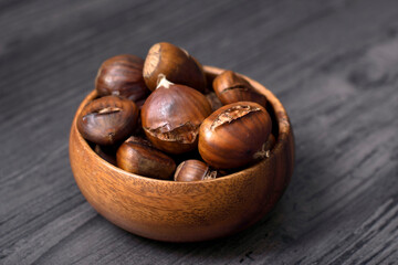 cooked chestnuts in wooden bowl and wooden background floor