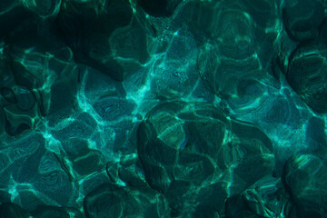 View from above to a stony seabed in clear water with abstract blue green pattern. Overview of the seabed seen from above, transparent water