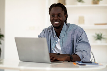 Fototapeta na wymiar Freelance Career. Portrait Of Young Smiling Black Man Working With Laptop