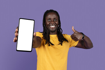 Cheerful cool black guy showing cell phone and thumb up