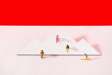 A white printed mountain with mini skiers on pale pink background with red sky above. Minimal...