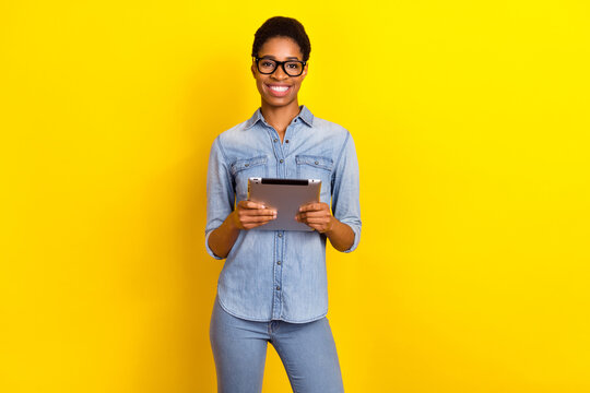 Photo of positive freelancer person hold digital tablet browsing chatting isolated on yellow color background - Powered by Adobe