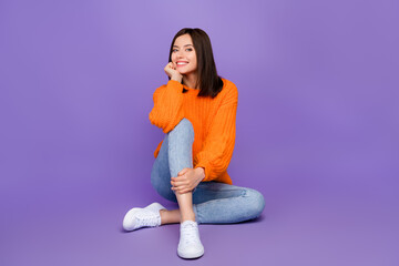 Full length photo of stunning young lady sitting floor shopping dressed stylish knitted orange garment isolated on purple color background
