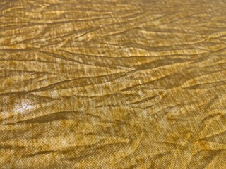 A yellow wrinkled wavy fabric surface