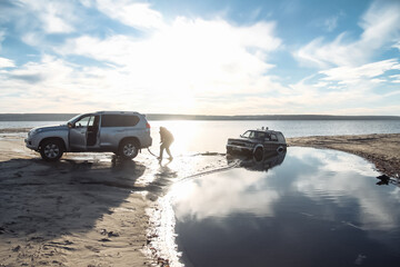 off-road vehicle trying to pull a stuck off-road vehicle out of the water