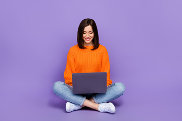 Full length photo of nice young lady sit floor work laptop coder dressed stylish orange knitted...
