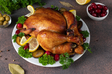 Grilled chicken on Thanksgiving day with plum, dogwood, lemon and parsley on brown background