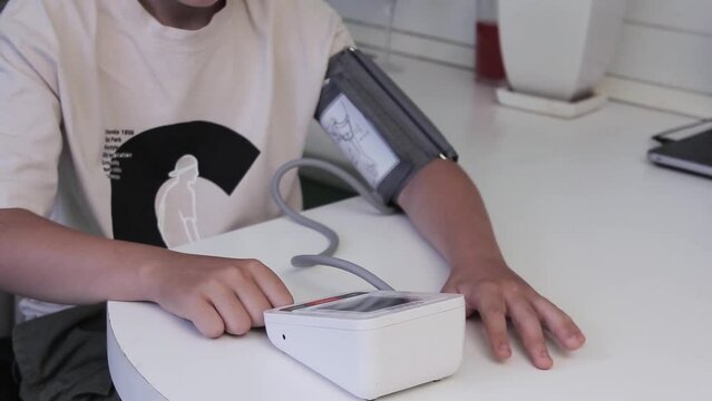 Guy measures the pressure with an electronic device at home