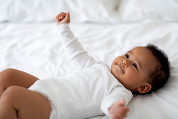 Closeup Portrait Of Cute Little African American Baby Lying On Bed