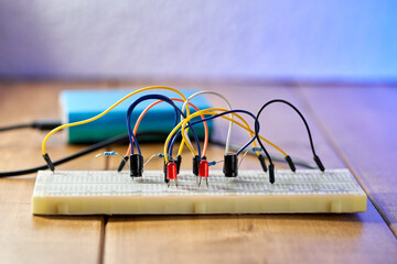 Breadboard with electrical elements, on a wooden table.