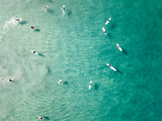 Aerial view of surfers floating in a circle over clear aqua  sea