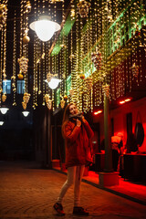 young woman at night in festive street lights