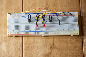 Breadboard with electrical elements, on a wooden table.