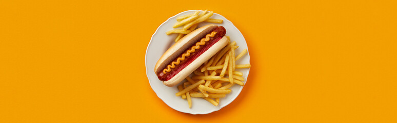 Traditional hot dog with french fries in plate on orange background. Restaurant menu