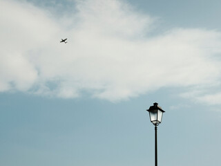 Black lantern under blue sky with flying plane