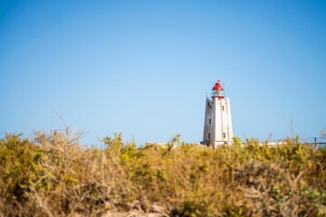 Closeup of a Lighthouse on a hill with a blue sky background