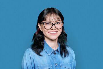 Smiling young female looking at camera on blue background