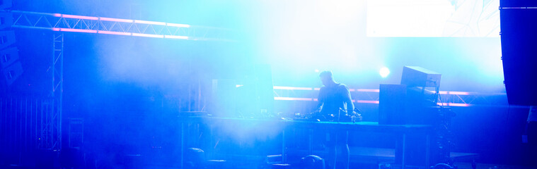 Dj playing techno music on the stage at night summer concert