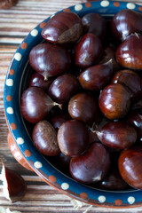 Chestnuts in a bowl on a rustic wooden table. Vertical shot. A close-up.