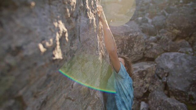 Rock climber climbs up boulder in boulder field