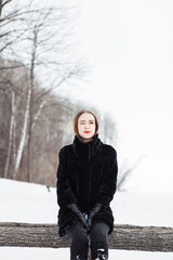 young fashionable woman walks in the forest in winter and uses a mobile phone