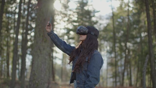 Young woman wearing virtual reality goggles, in the metaverse in nature