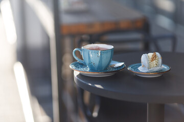 A cup of tea stands on a wooden table, the cup is filled with tea. To the right of a cup of macaroon. Autumn theme, wooden background. COPY SPACE.
