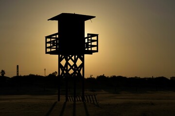 Silhouette of a guardhouse on the beach against the sun