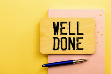 Well done Office desk with notepad and keyboard in the background. In black the handwritten text, well done.