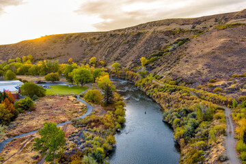 Aerial view of a beautiful River in Autumn with colorful trees, barren desert mountains, and a partly cloudy blue sky near Reno Nevada.