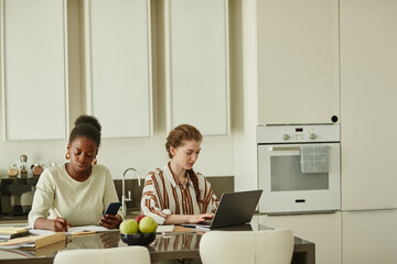 Portrait of two young women working together in minimal home setting, copy space