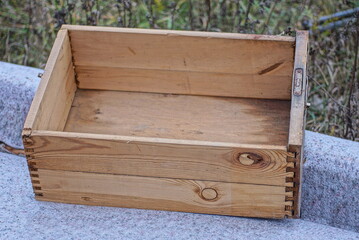 one old empty brown wooden box from the closet stands on a gray table in the street